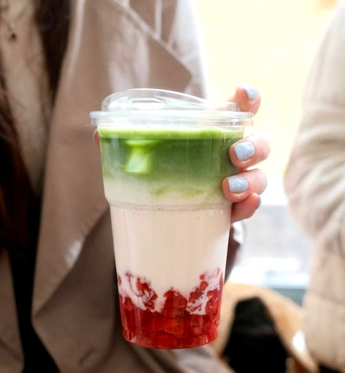 Frau hält Erdbeer-Matcha in der Hand in einem To-Go Becher